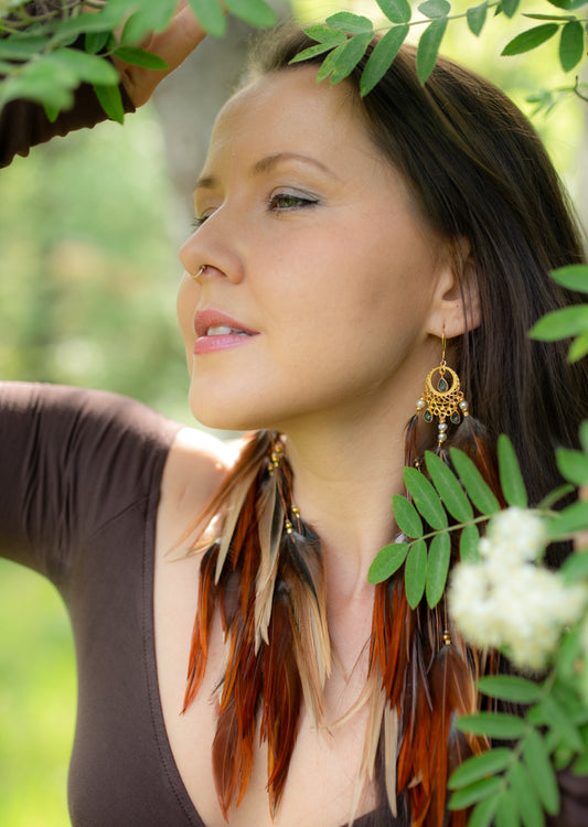 Beautiful feather earrings on woman with long brown hair.