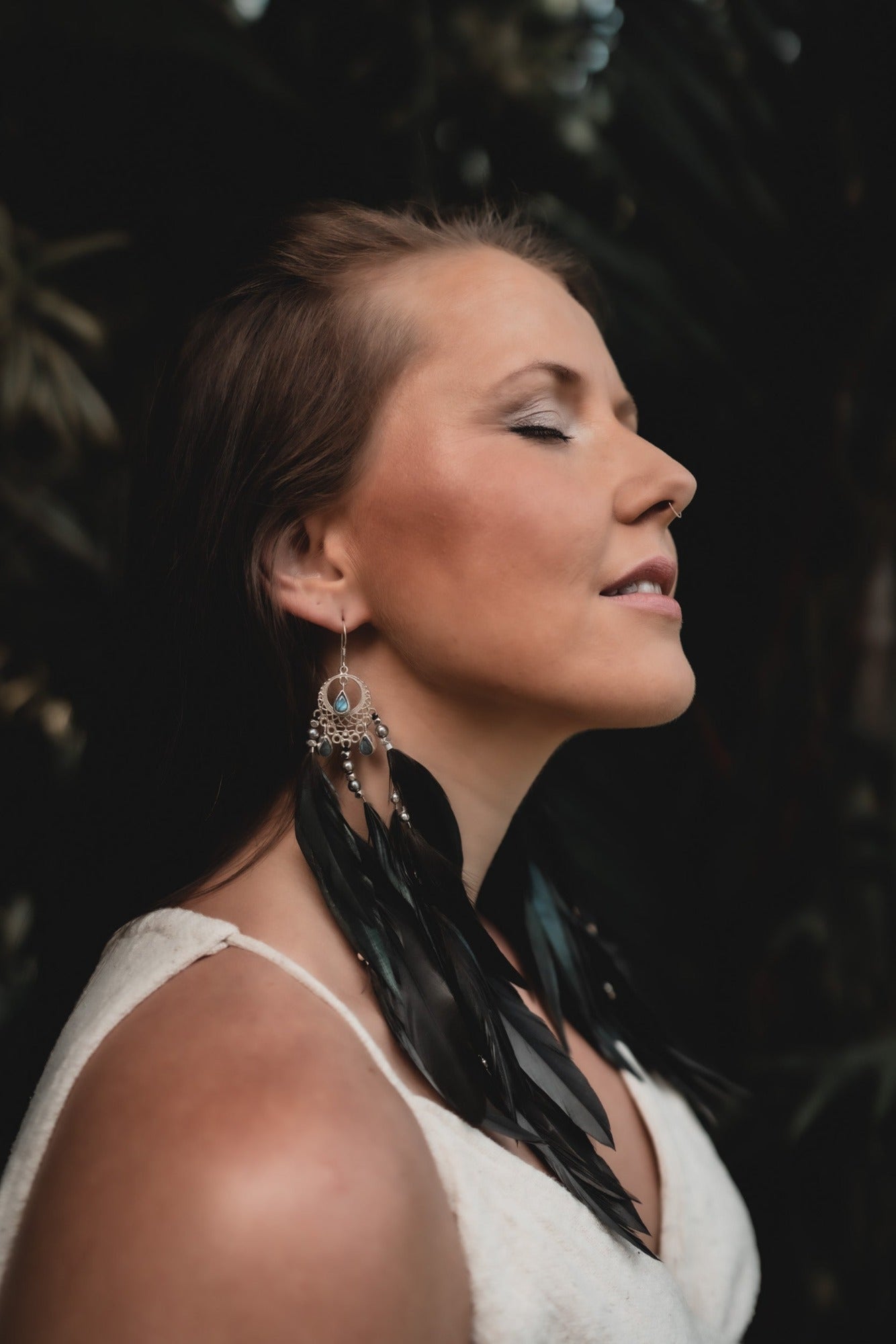 Silver and labradorite crystal earrings on woman with closed eyes and brown hair