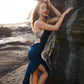 Beautiful dress with open back, side cuts and delicate strap details crossing the back in color dark teal.