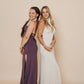 The brunette wearing a beautiful long halter dress, with a side cut in eggplant and the blonde wearing the same dress in winter white.