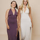 The brunette wearing a beautiful long halter dress, with a side cut in eggplant and the blonde wearing the same dress in winter white.